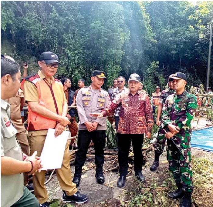 CEK LOKASI LONGSOR: Bupati Malang H M. Sanusi (dua dari kanan) meninjau titik jalan yang mengalami longsor kemarin (27/2).