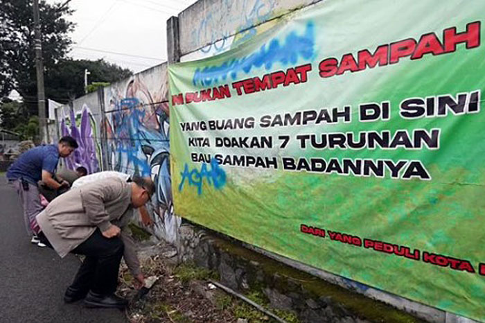 Pj Wali Kota Batu Aries Agung Paewai sedang memunguti sampah yang dibuang sembarangan