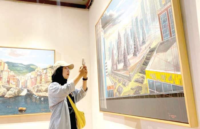 KAGUM: Salah seorang pengunjung menikmati karya seni dalam Pameran Tunggal Totarist Sosial Merbawani di Galeri Raos Minggu lalu (24/11).