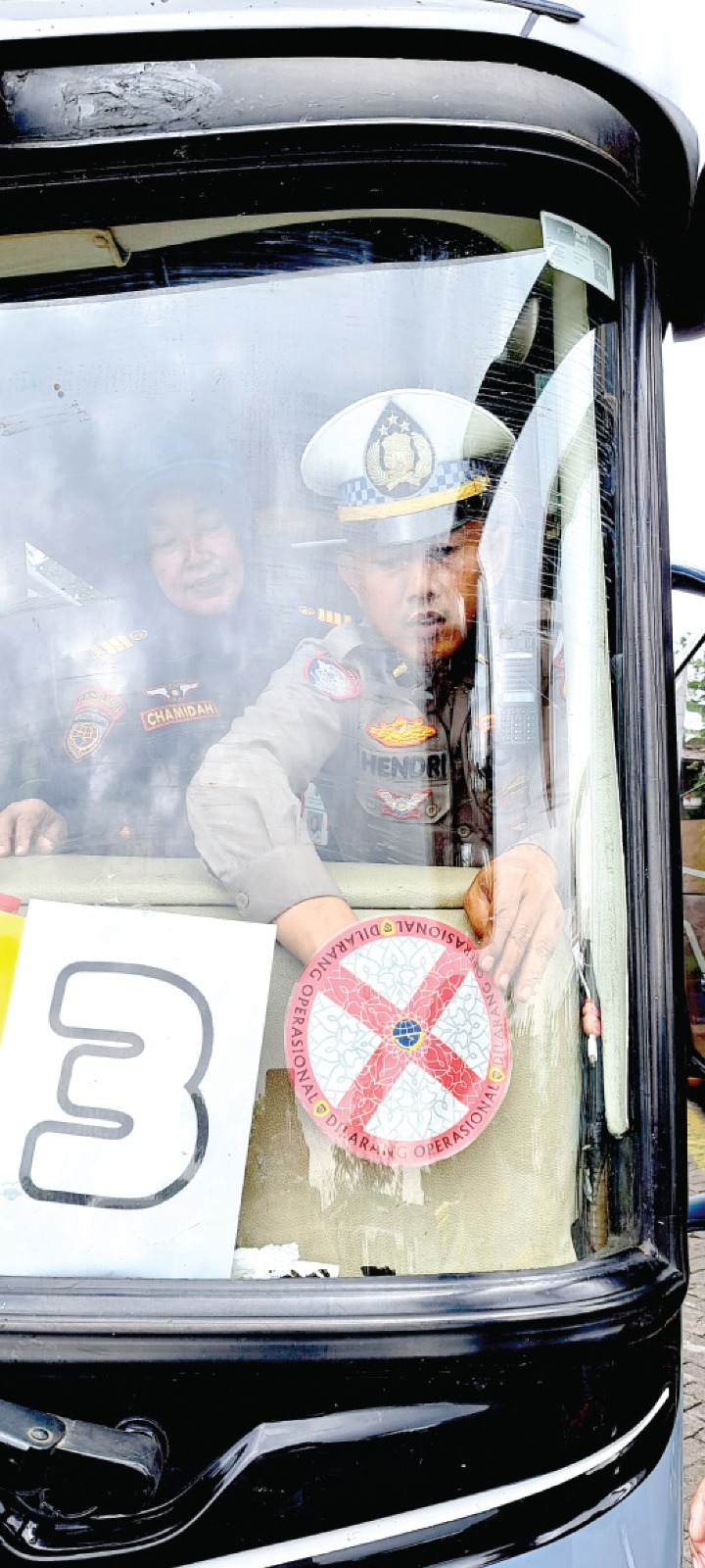 BERI PERINGATAN: Salah seorang petugas memasang stiker penanda tidak layak jalan di salah satu bus pariwisata di area parkir Museum Angkut beberapa waktu lalu. (DISHUB KOTA BATU FOR RADAR BATU)