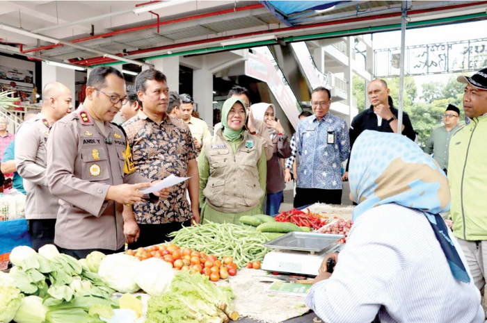 Kapolres Batu AKBP Andi Yudha Pranata sedang berdialog dengan salah seorang pedagang Pasar Induk Among Tani untuk menanyakan harga sejumlah komoditas kemarin (28/2). (POLRES BATU FOR RADAR MALANG)