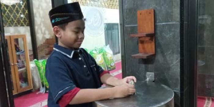 BERAMAL: Salah seorang anak memasukkan uang ke dalam kotak amal masjid di Kelurahan Temas, Kecamatan Batu kemarin