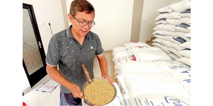 HARGA NAIK: Salah seorang penjual kedelai di Beji, Kecamatan Junrejo, menunjukkan biji kedelai impor miliknya. ( MOH RIZAL/RADAR BATU)