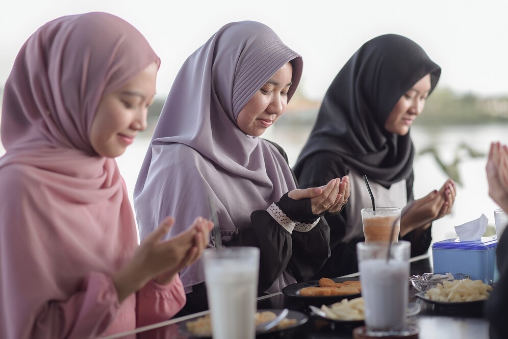 IlustrasitTiga wanita Muslimah sedang berdoa untuk bersiap menyantap santapan buka puasa. (freepik.com)