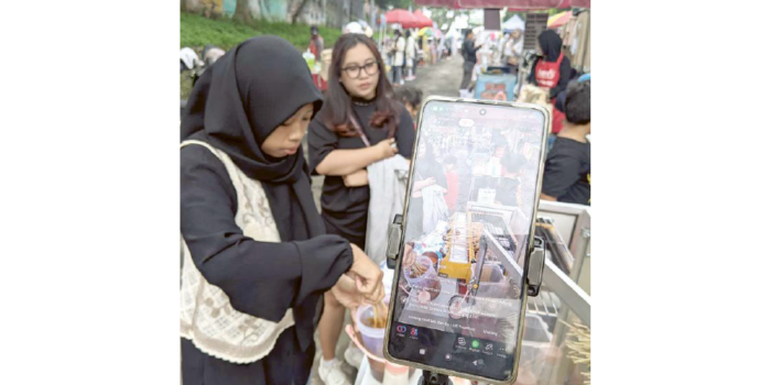 KREATIF: Salah seorang PKL CFD Mbatu Sae melakukan live streaming kemarin (RORI DINANDA BESTARI/RADAR BATU).