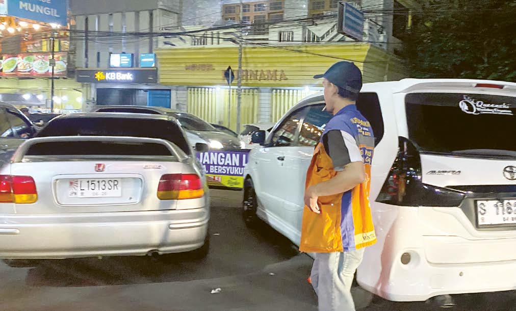 DITARGET RETRIBUSI: Salah seorang tukang parkir sedang menata parkir di kawasan Alun-Alun Kota Wisata Batu.