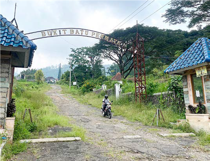 SEJAK 1996: Gapura menuju Perumahan Bukit Batu Permata di Desa Songgokerto, Kecamatan Batu tampak sepi dan jarang dilalui orang.