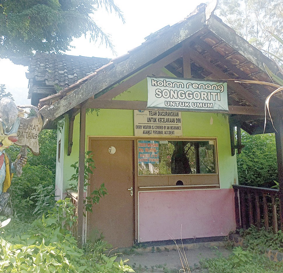 TERBENGKALAI: Pintu masuk kolam renang di Wisata Songgoriti tampak tak terurus dan ditumbuhi rumput liar kemarin (9/6).