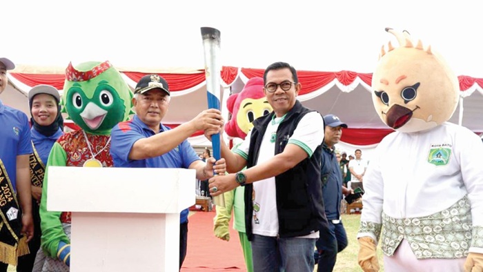 SERAH TERIMA: Bupati Malang H M. Sanusi menyerahkan obor Porprov IX Jatim ke Wali Kota Batu Nurochman di lapangan Desa Pendem, Kecamatan Junrejo kemarin (26/6). Obor tersebut kemudian diarak menuju Ba