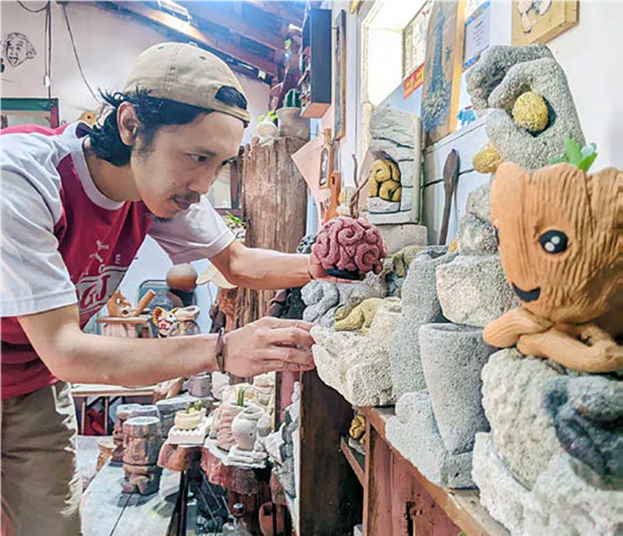 PEMINAT TINGGI: Tomi Adi Winarko merapikan sejumlah produk home decor yang dipajang di galerinya di Kampung UMKM Rejoso, Kecamatan Junrejo, Kota Batu, Minggu (29/6) lalu.