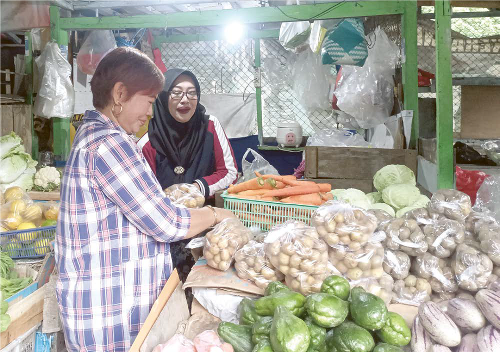 BERTAHAN: Puji Astutik, salah seorang pedagang di Pasar Wisata Songgoriti sedang menata sayuran yang dijajakannya beberapa hari lalu.