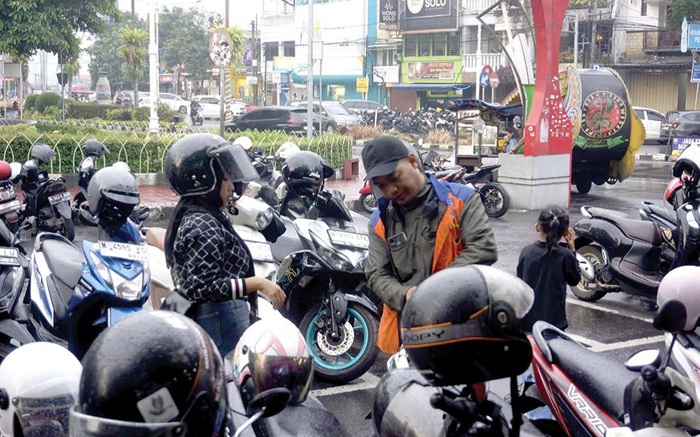 BERGELIAT: Salah seorang jukir membantu pengguna jasa parkir mengeluarkan kendaraannya beberapa hari lalu.