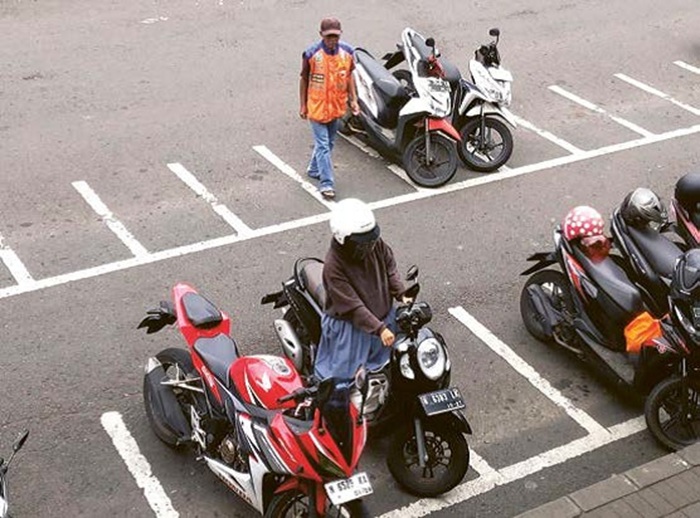 MASIH SERET: Salah seorang jukir di kawasan Alun-Alun Kota Wisata Batu tengah menata parkir kemarin (9/9).