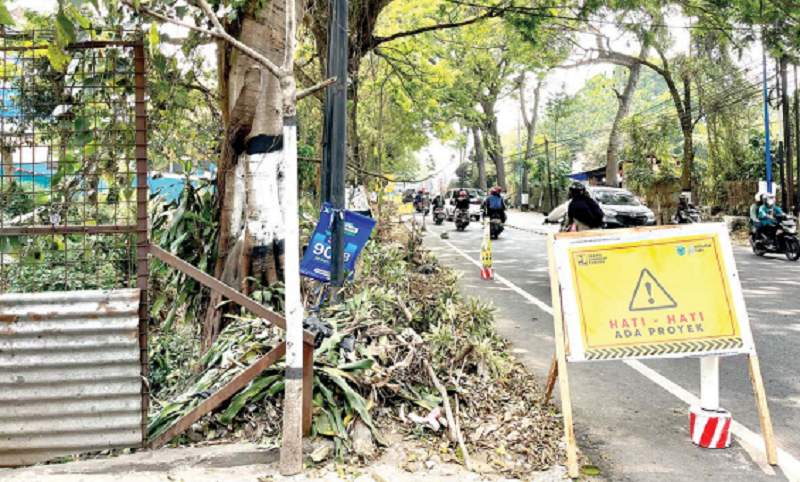 DIBERI PERINGATAN: Kondisi lokasi proyek pembangunan jembatan dan trotoar di depan SMP Negeri 3 Kota Batu penuh tumpukan sisa pemotongan pohon. Proyek itu diprediksi akan molor.