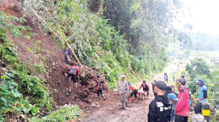 AMBROL: Tim BPBD Kota Batu bersama relawan setempat melakukan pembersihan material longsor di Jalan Anjasmoro, Desa Tulungrejo, Kecamatan Bumiaji kemarin (3/11).