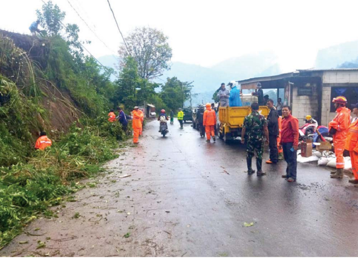 PROSES PENANGANAN: Personel Badan Penanggulangan Bencana Daerah (BPBD) Kota Batu memotong dan membersihkan area longsor di Desa Sumberbrantas kemarin siang (7/11).