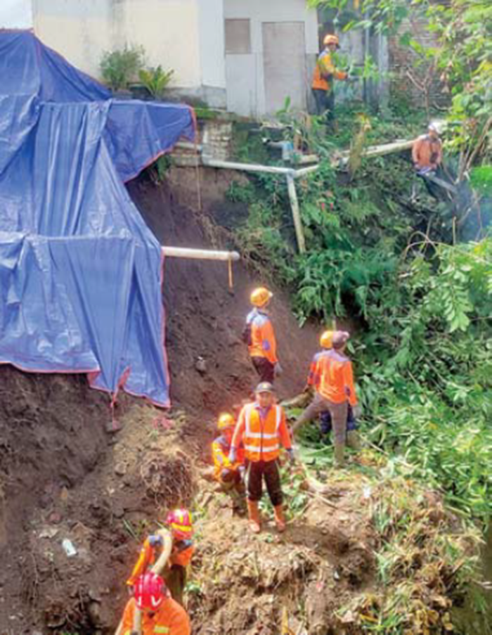 PROSES PEMBERSIHAN: Tim BPBD Kota Batu dan relawan setempat melakukan pembersihan material akibat longsor di Jalan Lesti, Kelurahan Ngaglik, Kecamatan Batu kemarin (18/11).