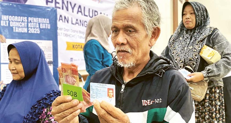 SEMRINGAH: Salah seorang warga senang usai menerima BLT DBHCHT di Kantor Desa Sidomulyo kemarin (19/11)