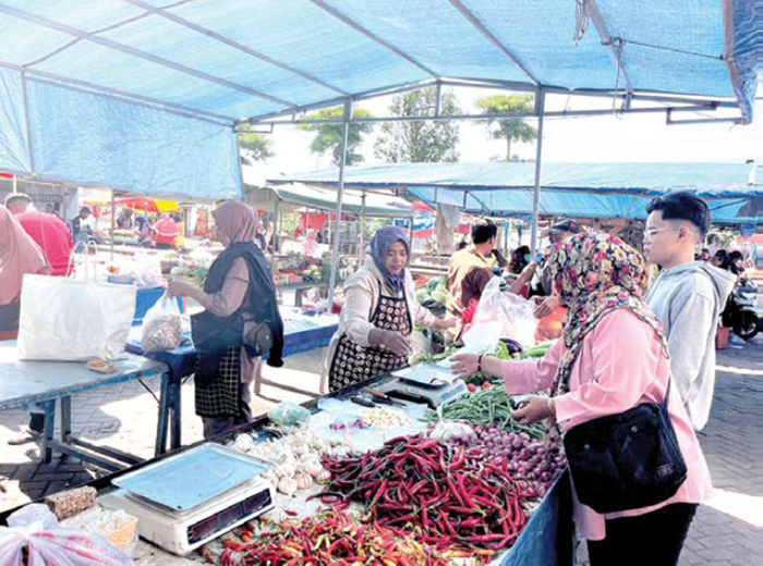 BERTRANSAKSI: Seorang pedagang di Pasar Pagi menjual cabai rawit merah kemarin (2/12).