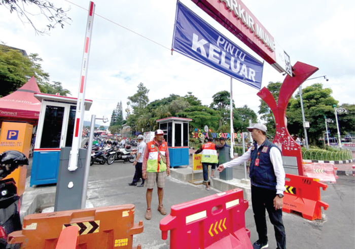 MULAI DICOBA: Petugas Dishub Kota Batu dan juru parkir mengecek pintu keluar parkir Alun-Alun Kota Wisata Batu pada Sabtu lalu (6/12).