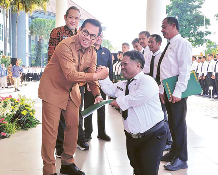 DAPAT LEGALITAS: Wali Kota Batu Nurochman menyerahkan SK pada Atim Jumaali, salah seorang PPPK paro waktu di halaman Balai Kota Among Tani Batu kemarin (16/12).