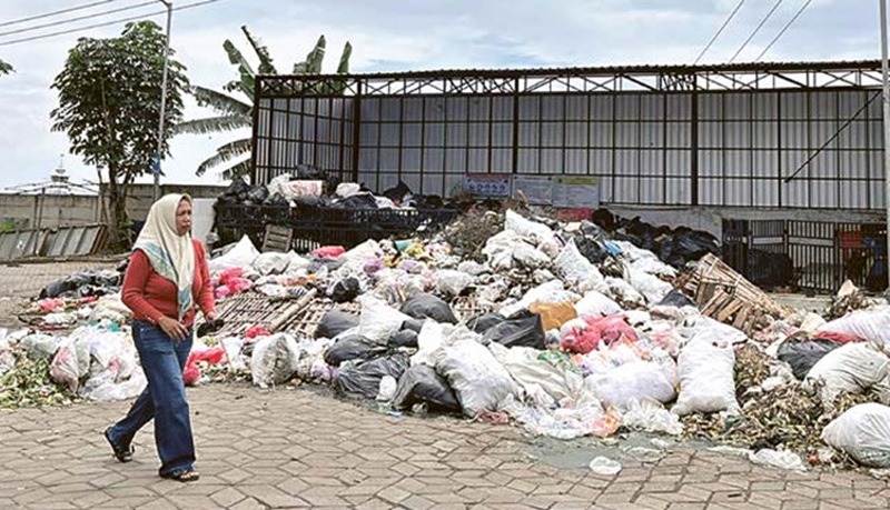 MENUMPUK: Sampah di TPS Pasar Induk Among Tani tetap berserakan hingga menutup sebagian jalan meski telah dipasang pagar permanen kemarin (19/12).
