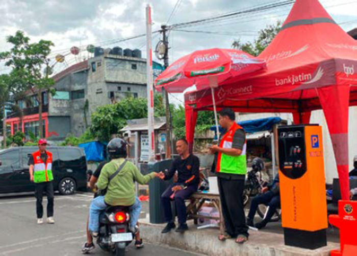 TAK KUNJUNG DIUJI COBA: Petugas parkir Alun-Alun Kota Wisata Batu menarik karcis parkir dari pengunjung kemarin (25/12).