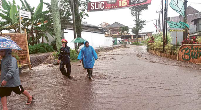 DIBERSIHKAN: Marerial lumpur setebal 20 sentimeter di Jalan Banaran, Desa Bumiaji, Kecamatan Bumiaji dibersihkan hingga malam hari oleh tim gabungan pada Rabu lalu (24/12).
