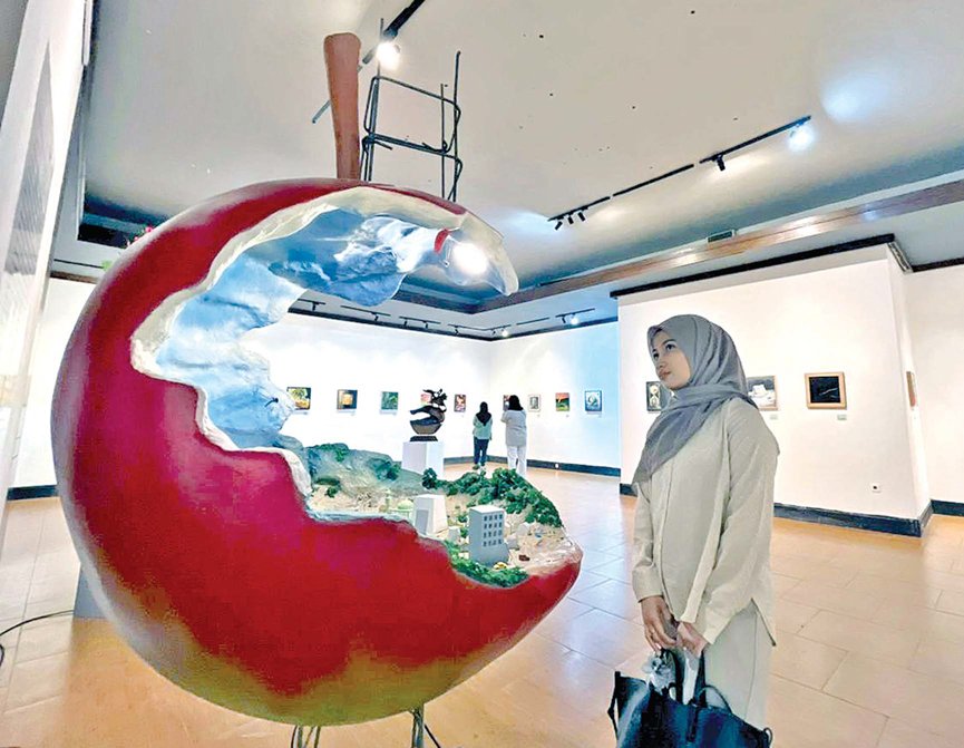 IRONI: Salah seorang pengunjung mengamati instalasi seni bertajuk Pray For Batu karya Agus Sujito dalam pameran bertema &ldquo;Garis Hijau&rdquo; di Galeri Raos. (Zanadia Manik/Radar Batu)