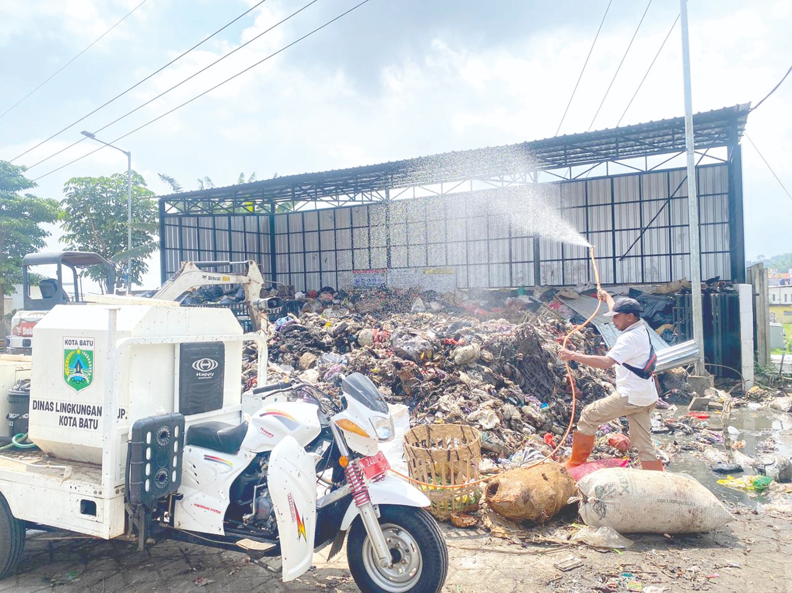 SEGERA DIANGKUT: Petugas kebersihan melakukan penyemprotan di TPS Pasar Induk Among Tani Batu kemarin (30/1).