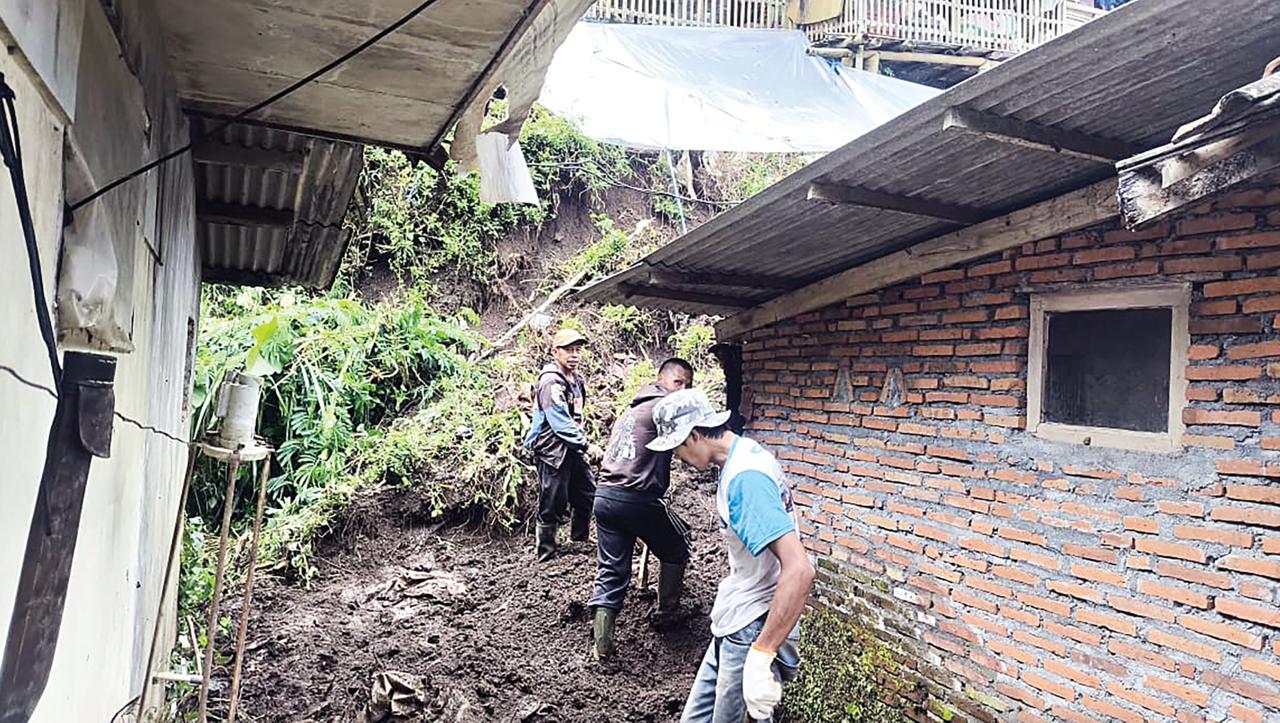 DITERJANG LONGSOR: Tim BPBD dan warga melakukan pembersihan material longsor di Dusun Brau, Desa Gunungsari, Kecamatan Bumiaji kemarin (1/2).