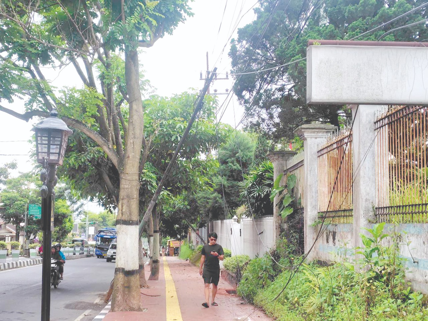 BUTUH PERHATIAN: Salah satu kabel semrawut di Jalan Trunojoyo, Kelurahan Songgokerto berpotensi membahayakan pejalan kaki.