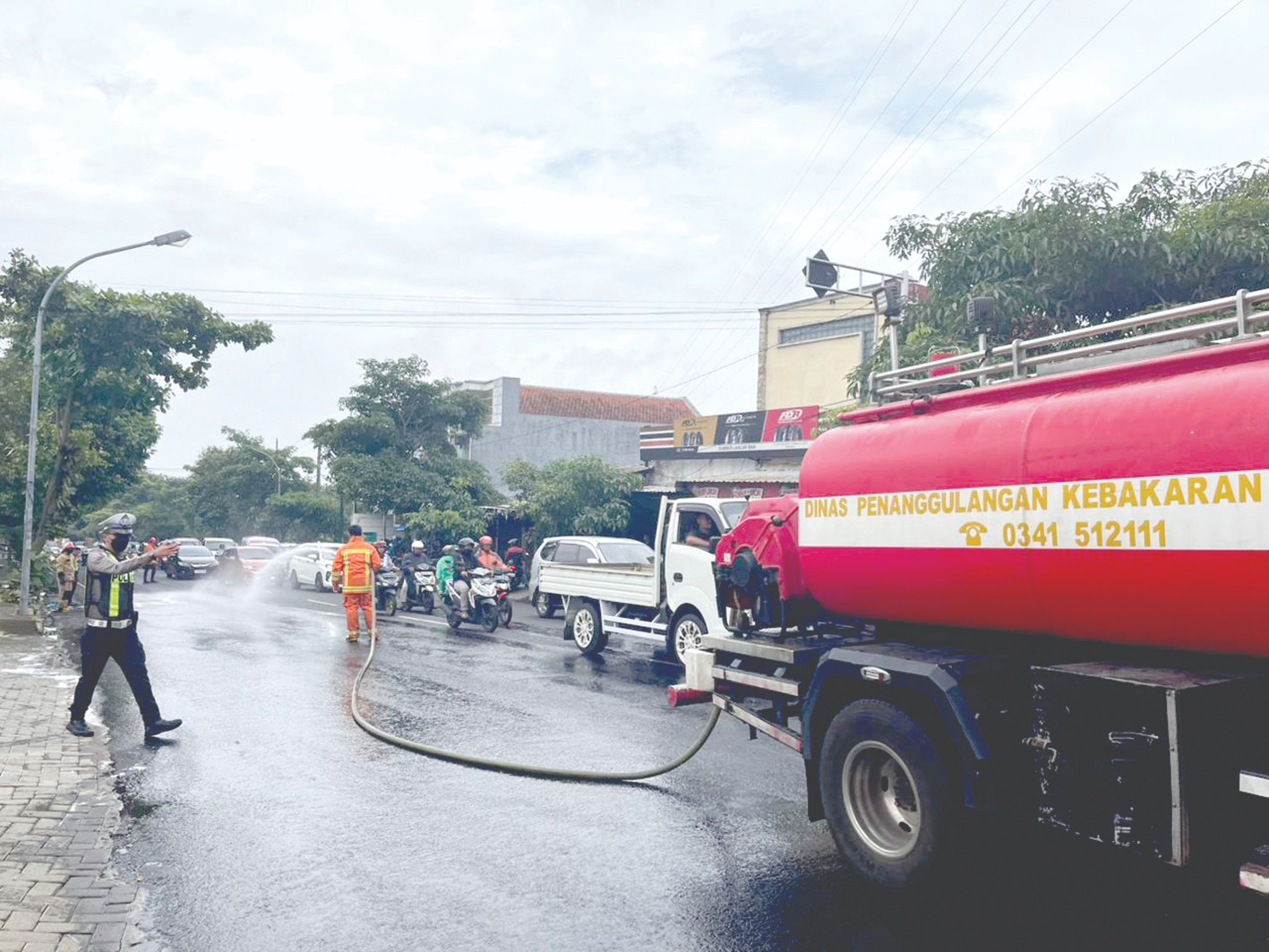 PROSES STERILISASI: Tim damkar membersihkan kawasan Jalan Dewi Sartika yang terkena tumpahan solar bocor kemarin (10/2).