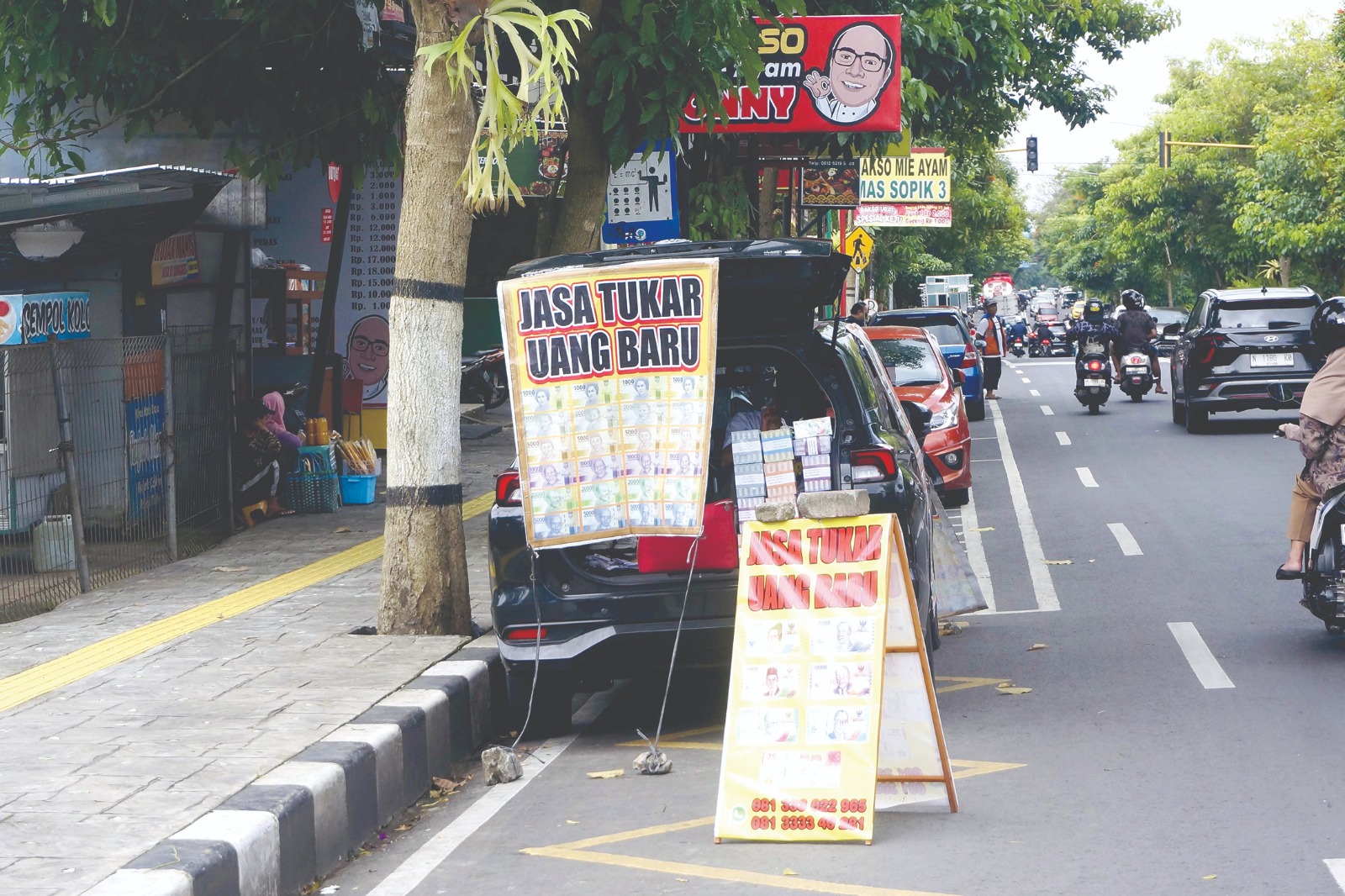PERLU WASPADA: Salah seorang warga menerima jasa penukaran uang baru di Jalan Gajahmada, Kelurahan Sisir, Kecamatan Batu kemarin (11/3).