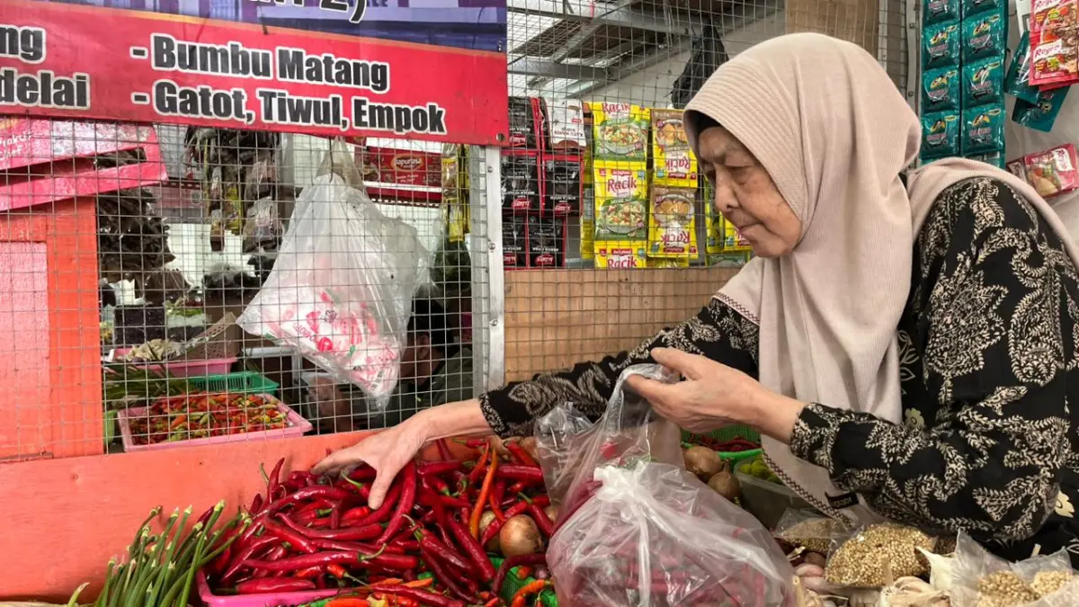 MELAYANI PEMBELI: Siti Aminah, salah seorang pedagang sayur mayur di Pasar Induk Among Tani melayani pembeli cabai beberapa hari lalu. ZANADIA MANIK FATIMAH/RADAR BATU