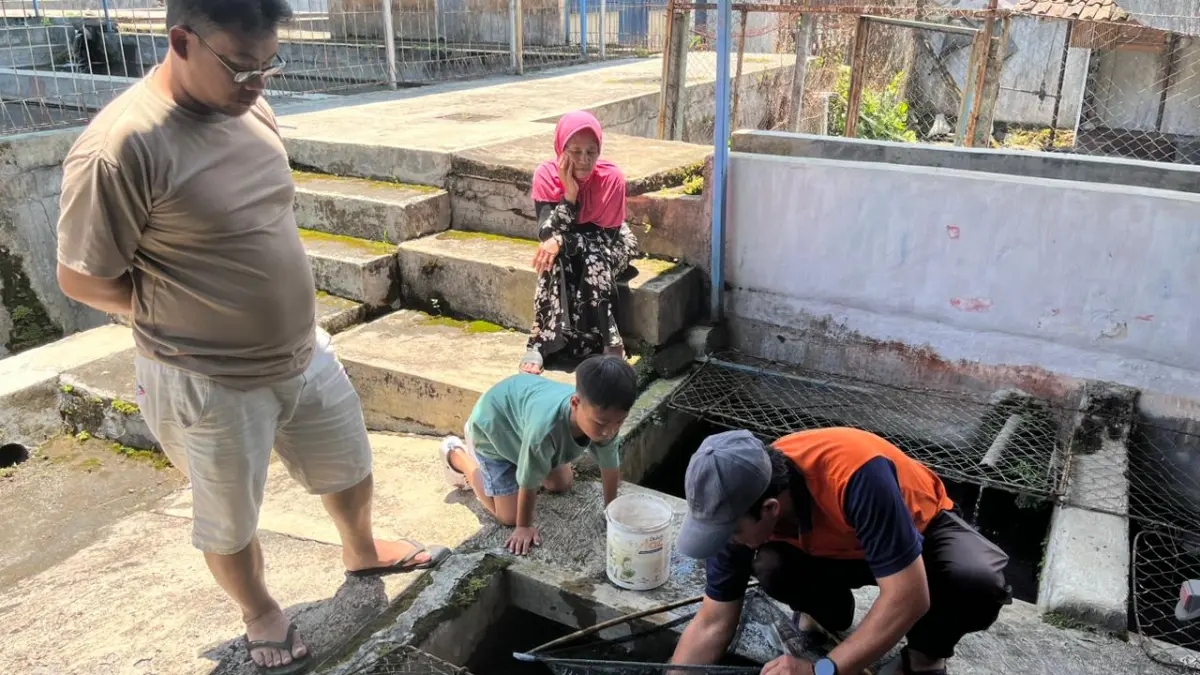 TRANSAKSI JUAL BELI: Salah seorang pedagang ikan mas dan komet di Pasar Ikan, Desa Sidomulyo, Kecamatan Batu melayani pembeli beberapa hari lalu. (ZANADIA MANIK FATIMAH)