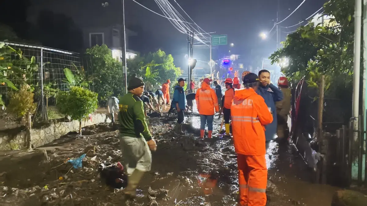 BPBD Kota Batu dibantu warga membersihkan lumpur sisa bekas banjir yang melanda sejumlah wilayah di Bumiaji, Senin (30/3). (PUSDALOPS BPBD KOTA BATU FOR RADAR BATU)