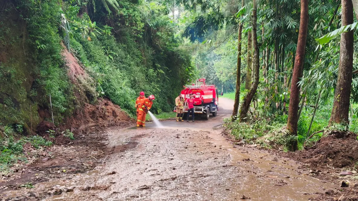 Petugas membersihkan tanah longsor di jalan Pura Luhur Giri Arjuno. (Pusdalpops BPBD Kota Batu for Radar Batu)