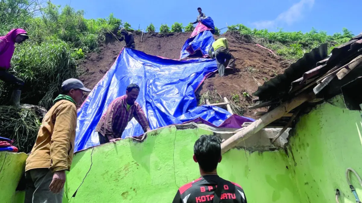 PENANGANAN: Tim BPBD Kota Batu dibantu warga menyalurkan bantuan terpal untuk penanganan pascabencana tanah longsor yang menimpa atap rumah warga Desa Sumberbrantas, Kecamatan Bumiaji kemarin (13/4). BPBD KOTA BATU FOR RADAR BATU 