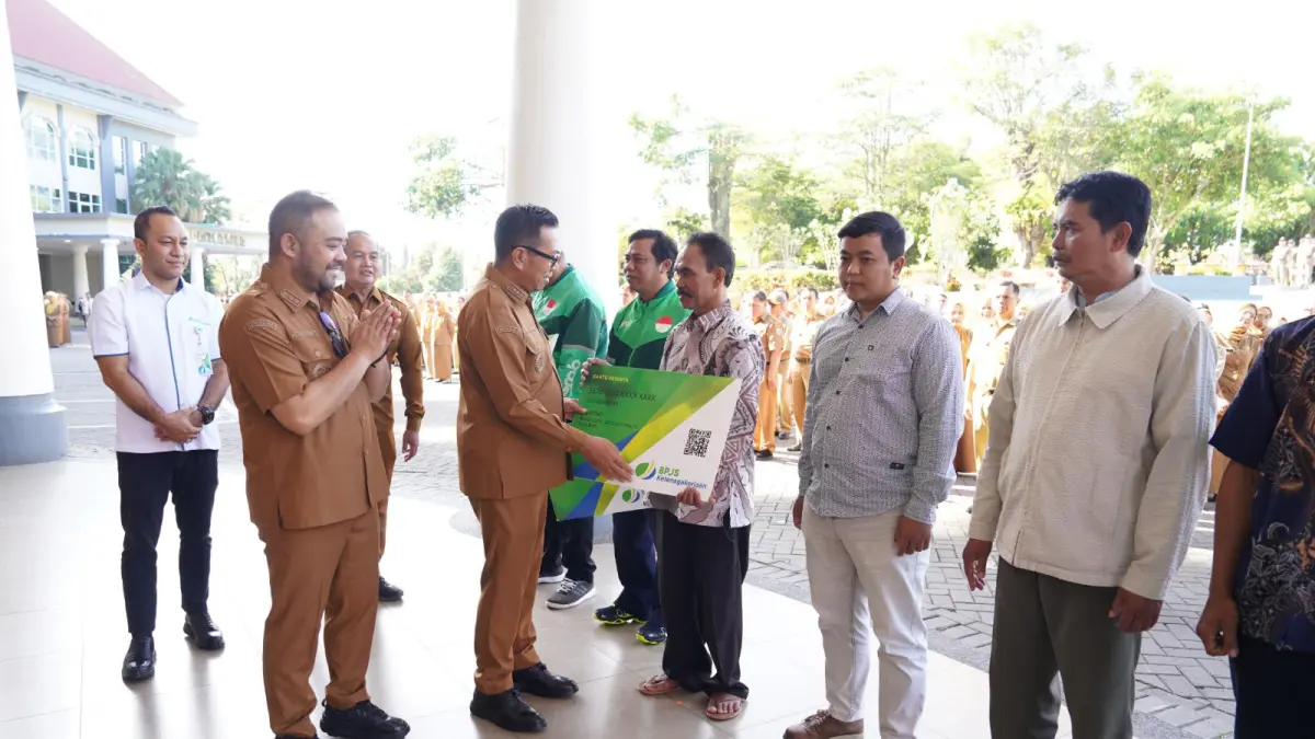 TERIMA BANTUAN: Wali Kota Batu Nurochman menyerahkan secara simbolis kartu BPJS Ketenagakerjaan kepada pekerja informal saat apel pagi di Balai Kota Among Tani kemarin (20/4). PROKOPIM KOTA BATU FOR RADAR BATU