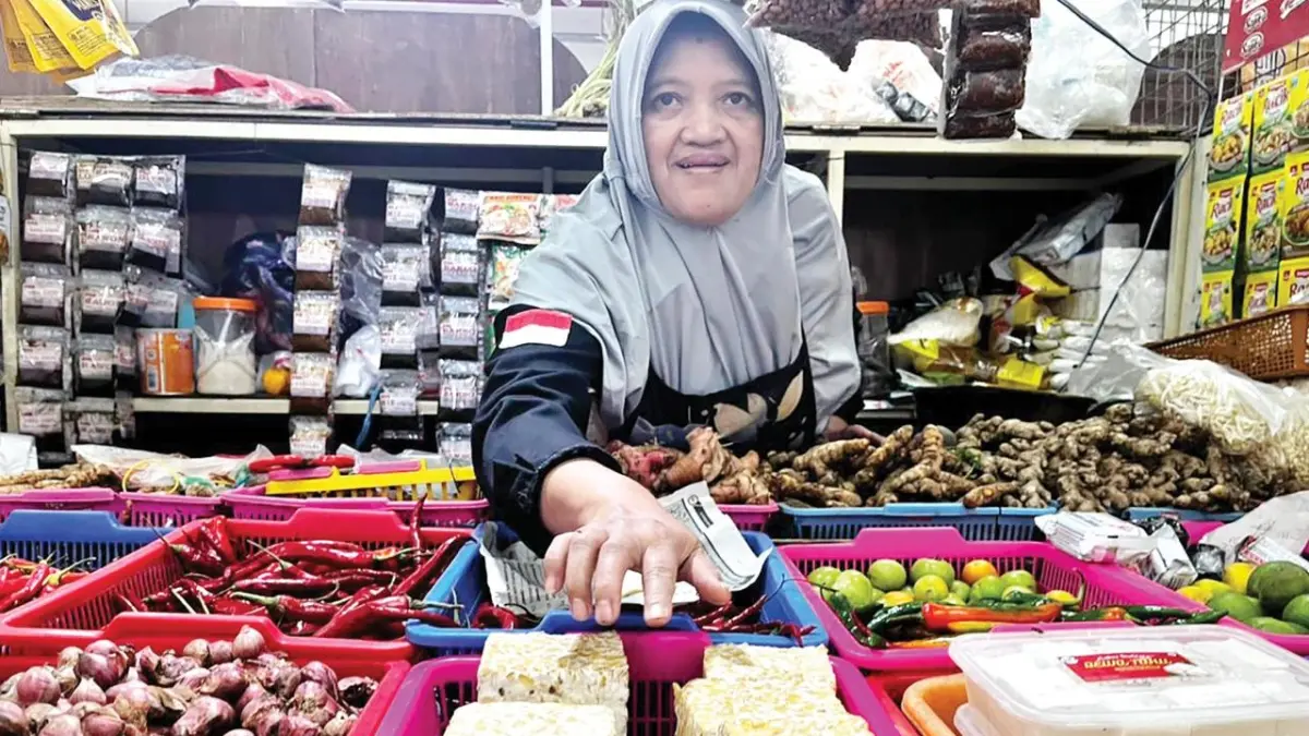 UKURAN SUSUT: Salah seorang pedagang di Zona Sayur Pasar Induk Among Tani hendak meraih potongan tempe yang dijajakannya kemarin (5/5). 