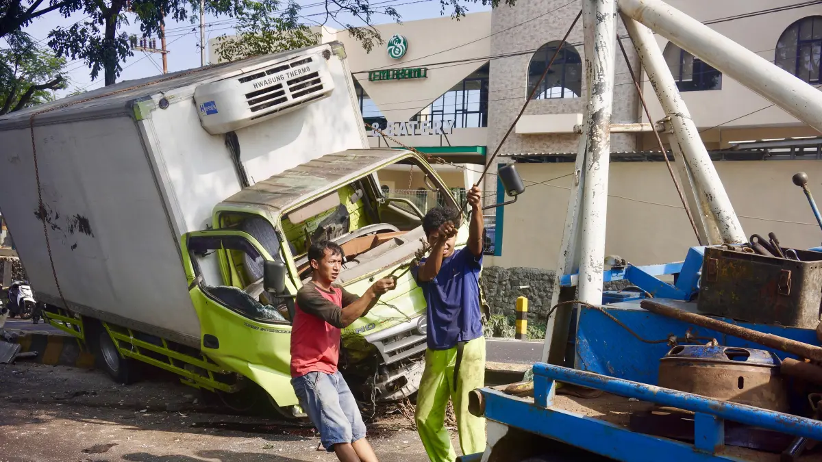 PROSES EVAKUASI: Mobil derek dikerahkan untuk membantu mengevakuasi Truk Hino yang tersangkut di median jalan Ir Soekarno, Kecamatan Junrejo kemarin (8/5)