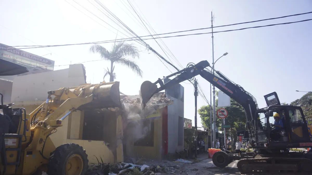 PROYEK REVITALISASI: Dua alat berat dikerahkan untuk membongkar pos polisi di Simpang Patih Kota Batu beberapa hari lalu.