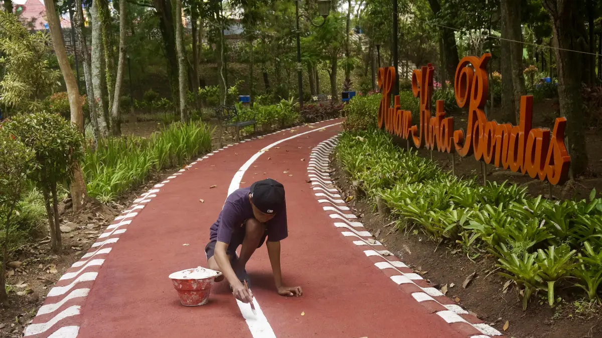 PROSES PENGERJAAN: Salah seorang petugas di lapangan melakukan pengecatan jogging track di Taman Hutan Bondas beberapa hari lalu.
