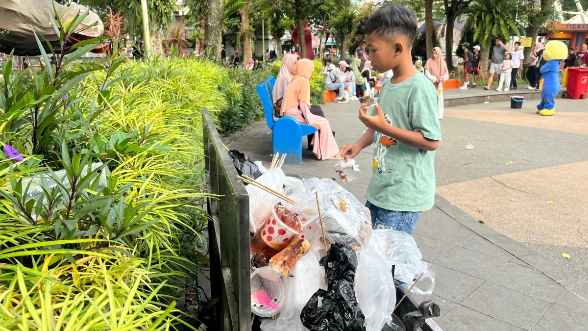 KOTOR: Sejumlah pelancong membuang sampah pada bak penampungan yang telah meluber di Alun-Alun Kota Wisata Batu pada Minggu lalu (17/5). Minat berwisata yang tinggi belum diikuti oleh kesadaran menjaga kebersihan ruang publik.