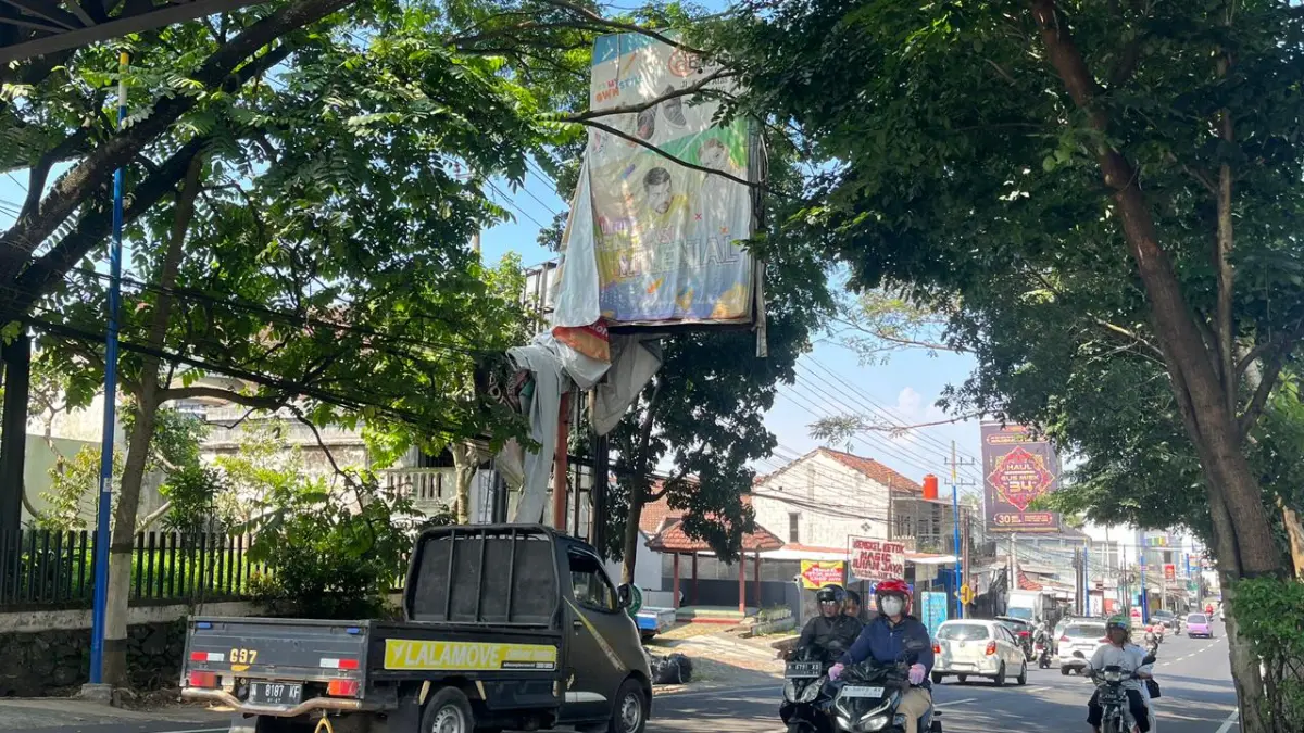 MENGGELANTUNG: Salah satu reklame tampak menggantung pada kabel listrik di Jalan Ir Soekarno kemarin (23/5).