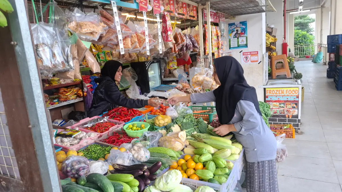 JUAL BELI: Salah seorang pedagang sayur-mayur dan kebutuhan dapur melayani konsumen beberapa hari lalu.