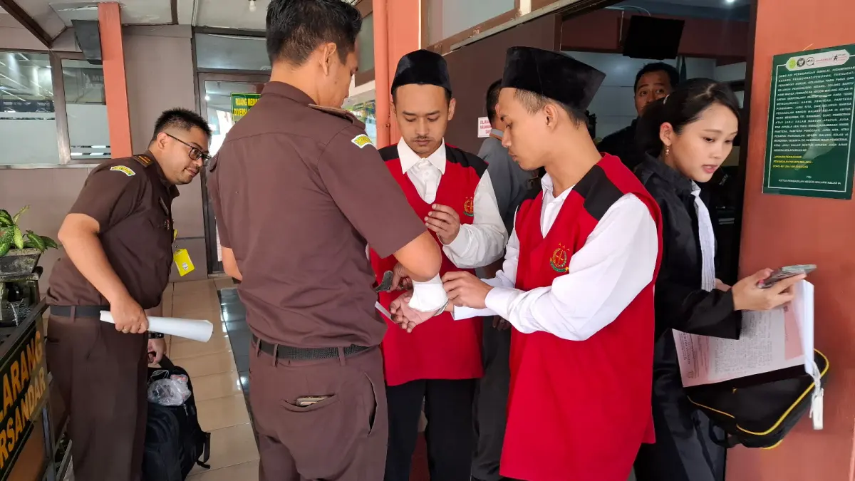PENCURIAN: Tersangka pencurian logam mulia dipasangkan borgol oleh pengawal tahanan setelah keluar dari ruang sidang Pengadilan Negeri Kota Malang Rabu lalu (10/6).
