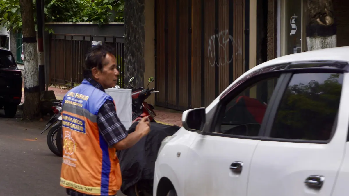 RETRIBUSI MINIM: Seorang juru parkir (jukir) menata kendaraan di Jalan Panglima Sudirman, Kecamatan Batu, kemarin (23/6). Pemkot Batu menyoroti rendahnya setoran retribusi parkir tepi jalan yang memicu kebocoran PAD.