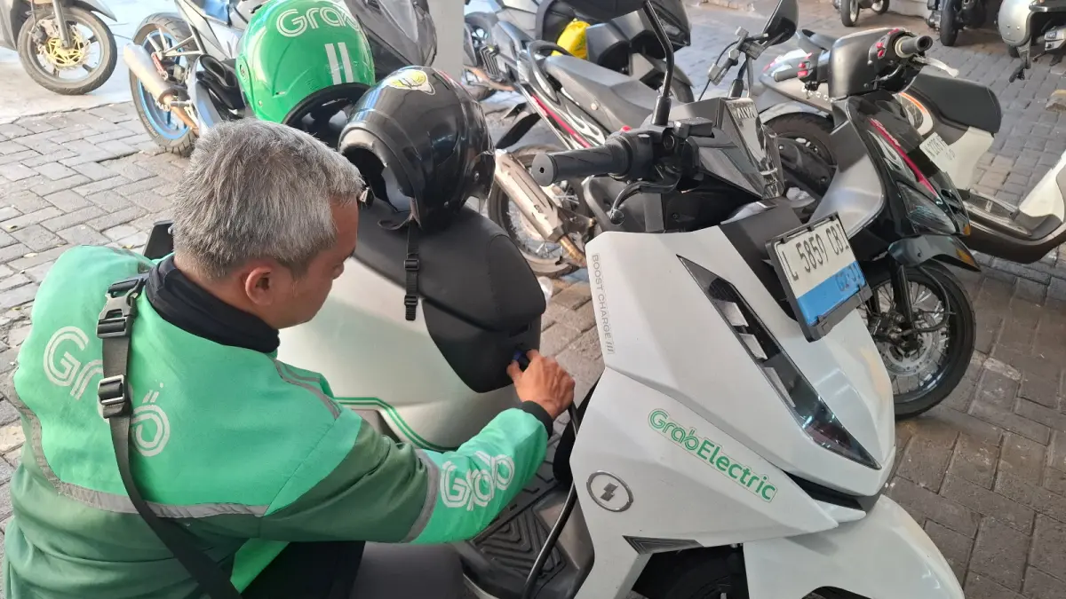 
MOLIS OJOL: Pengemudi ojek online (ojol) mengisi daya listrik kendaraannya di salah satu stasiun pengisian minimarket Kota Batu, beberapa hari lalu.